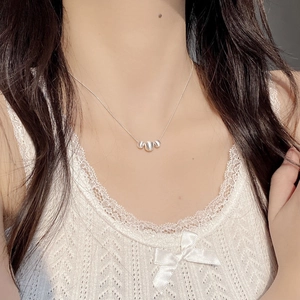 Close-up of three brushed silver spheres on a delicate chain worn on a woman's neck