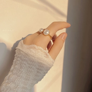 Detail of U-shape silver ring with double freshwater pearls worn on a female hand