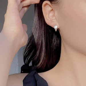 Close-up of a silver shell-shaped earring with fine vertical stripes on female model
