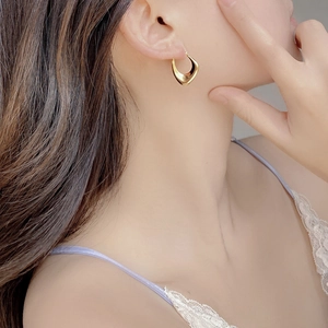 Detail of minimalist geometric square gold ear cuff with polished mirror finish on model
