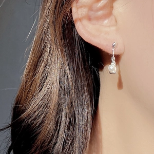 Macro view of sterling silver earrings with natural pearls on model's ear