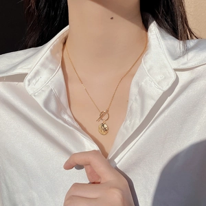 Detail of gold 925 silver necklace with textured round coin pendant and OT clasp