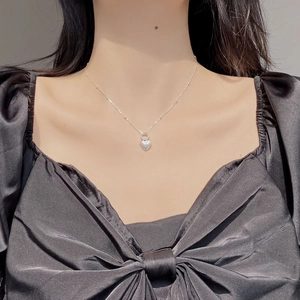 Close-up of a silver heart pendant necklace with radial texture worn on a model