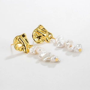 Detailed shot of gold irregular metal earrings with hanging white baroque pearls