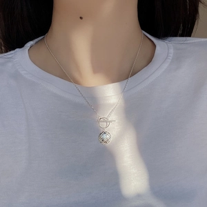 Detailed view of sterling silver necklace with hollow spherical pendant and OT toggle clasp