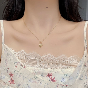 Golden bead chain necklace with laser-textured heart pendant on a floral dress