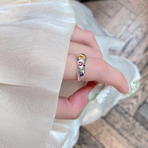 Hand wearing an irregular silver ring with four colorful heart-shaped zircons