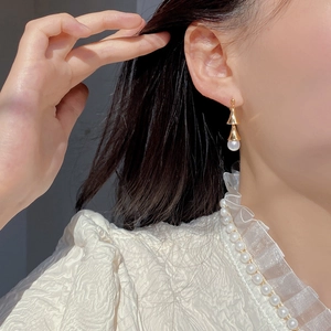 Gros plan de boucles d'oreilles cloches dorées avec perles naturelles sur modèle