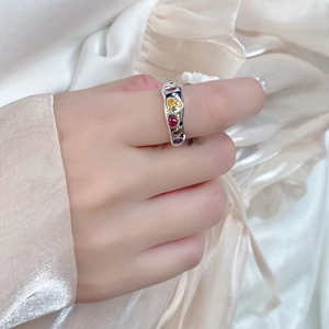 Macro view of sterling silver ring with irregular fluid design and colorful heart zircons