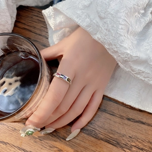 Detailed view of silver irregular geometric ring with three colored zircons on hand