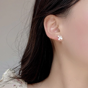 Détail de boucles d'oreilles fleur de gardénia en argent S925 mat portées par un mannequin