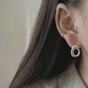 Close-up of minimalist 925 sterling silver hollow oval studs on model ear