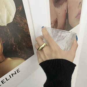 Detail of a chunky gold teardrop ring worn on index finger with minimalist style