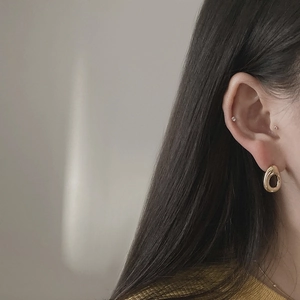 Close-up of a gold teardrop earring with high-polish finish worn by a model