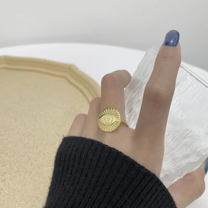 Detail of vintage golden evil eye coin ring on model hand with glass background