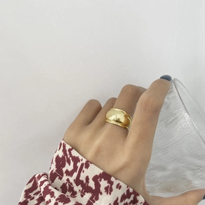Detail of a minimalist gold wide band ring with a polished mirror finish on model