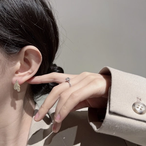 Nahaufnahme eines goldenen Herz-Ohrrings und eines rechteckigen Edelsteinrings