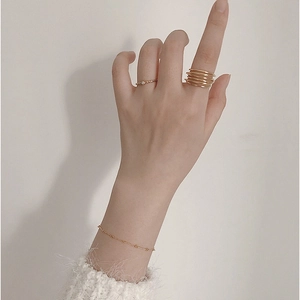 Detail of stacked gold S925 silver rings and beaded bracelet on hand in warm lighting