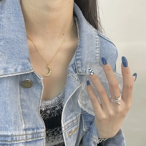 Detail of a vintage golden crescent moon necklace and twisted snake ring on model