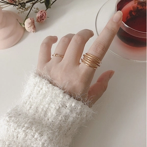 Close-up of gold layered wrap ring and textured band set on model's hand with cozy vibe