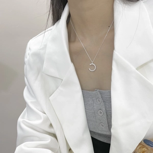Détail du collier lettre C en argent sterling S925 porté sur un blazer blanc