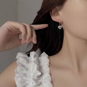 Detail of 925 sterling silver heart earrings worn by a model in soft lighting