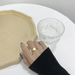 Detailed view of a gold round disk ring with a twisted band worn on a finger