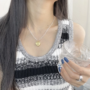 Détail d'un pendentif cœur 3D doré sur chaîne trombone argentée avec bague ouverte