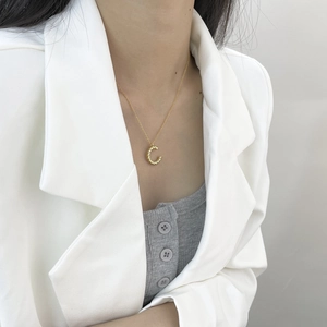 Détail du collier lettre C dorée avec texture torsadée porté par un mannequin