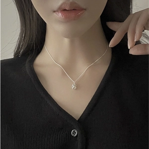 Detail of irregular natural pearl pendant on 925 silver necklace worn by model