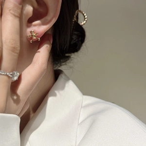 Close-up of a model wearing a polished gold bear stud earring with a minimalist blazer