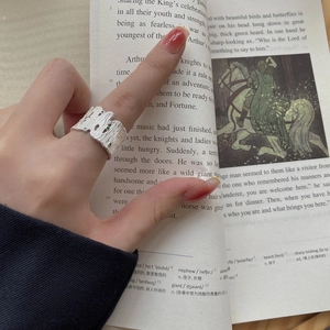 Close-up of 925 silver tree bark texture ring with three green gemstones on a book