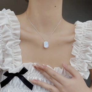 Close-up of elegant baroque pearl pendant on a silver chain worn by a model