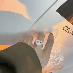 Détail d'une bague coeur en argent 925 avec zircons roses et verts portés au doigt