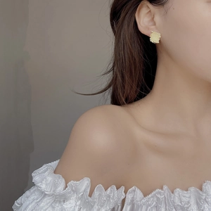 Golden square stud earrings with woven mesh texture on a model side profile view