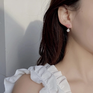 Detail of elegant natural freshwater pearl earring worn by model in a soft lighting