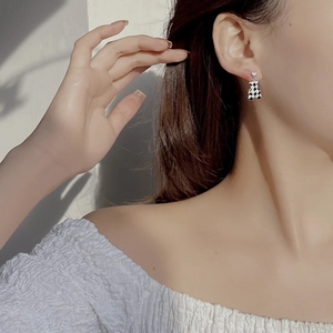 Gros plan d'un mannequin portant des boucles d'oreilles ours à damier noir et blanc