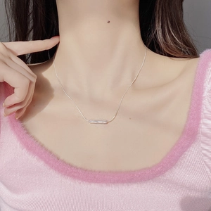 Detail shot of a minimalist S925 sterling silver bar pendant on a delicate chain necklace