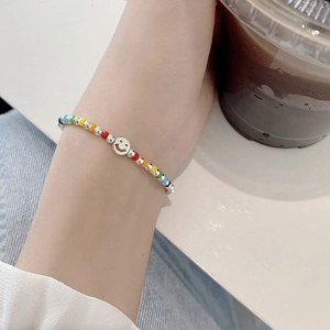 Detailed view of colorful beaded smiley face silver bracelet on wrist with coffee cup