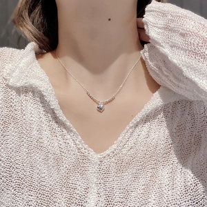 Gros plan du collier avec pendentif cœur en argent 925 sur un mannequin en tricot blanc