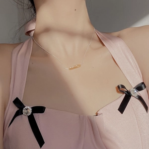 Detail of minimalist S925 silver necklace with amber-toned cylindrical bar pendant