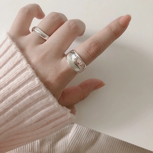 Detail of two minimalist polished S925 silver rings worn on fingers with a pink knit sleeve