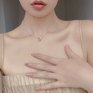 Detail of 925 silver ball chain necklace with a contrast gold ring pendant on model