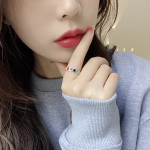 Close-up of a silver smiley face ring with colorful enamel inlay on a person's finger