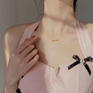 Close-up of minimalist S925 silver necklace with golden cylinder pendant on neck
