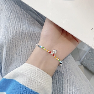 Close-up of colorful beaded heart charm bracelet worn on wrist over denim background