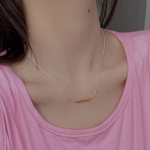 Close-up of S925 sterling silver snake chain with a minimalist gold bar pendant on a model