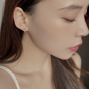 Detail of silver rose stud earring with gold petals on a female model wearing it