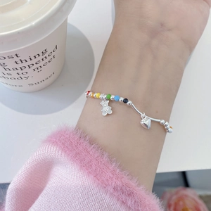 Détail du bracelet en argent s925 avec perles arc-en-ciel et breloques ours et cœur au poignet