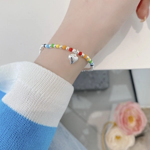 Detailed close-up of rainbow beaded heart charm bracelet worn on a woman's wrist